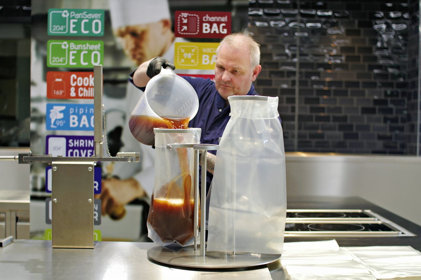 Mann füllt heiße Speisen in einen Cook & Chill Beutel mit Abfüllstation in einer Profiküche.